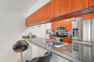a kitchen with stainless steel appliances and wooden cabinets at Luxury Bayview Condo | Pool, Gym & Skyline Views in Miami