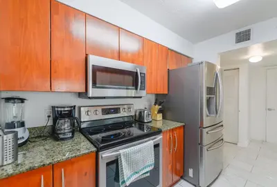 a kitchen with stainless steel appliances and wooden cabinets at Luxury Bayview Condo | Pool, Gym & Skyline Views in Miami