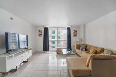 a living room with a couch and a flat screen tv at Luxe 2BD Unit | W Sauna, Pool & Gym access in Miami