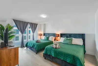a bedroom with two beds with green sheets and a tv at Luxury 2BD Condo | Sauna, Pool & Resort Access in Miami