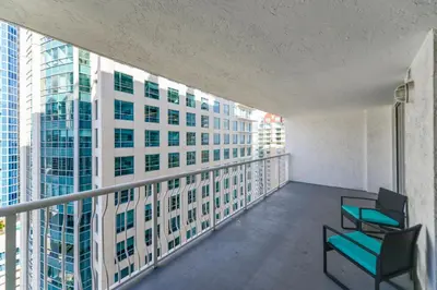 a balcony with chairs and a view of a building at Luxury 2BD Condo | Sauna, Pool & Resort Access in Miami