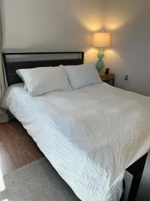 a bed with white sheets and a lamp on a table at Cozy Home away from home! in Miami