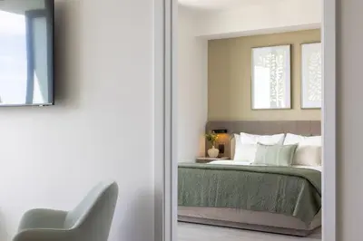 a bedroom with a bed with green sheets and a chair at 72 Park Ocean view 1BR Apartment with Pool and Gym in Miami Beach
