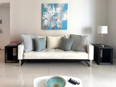 a living room with a white couch with blue pillows at Modern 1B at Icon Brickell 32nd fl Pool Spa Gym FREE Parking Scenic view in Miami