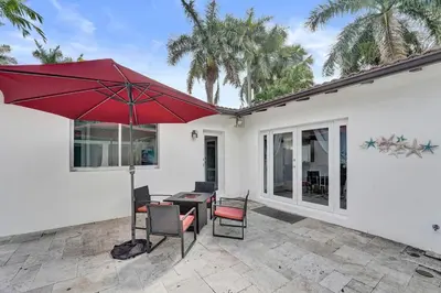 a patio with a table and chairs and a red umbrella at Oasis 5 Bed, 3 Bath Pool Home Minutes to the Beach in Hollywood