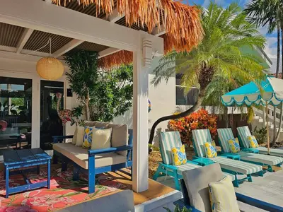 a patio with chairs and tables and a palm tree at The Bird-2 blocks to beach-Heated Pool-Hot Tub in Fort Lauderdale