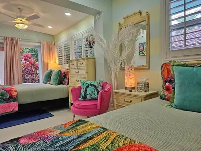 a bedroom with two beds and a pink chair at The Bird-2 blocks to beach-Heated Pool-Hot Tub in Fort Lauderdale
