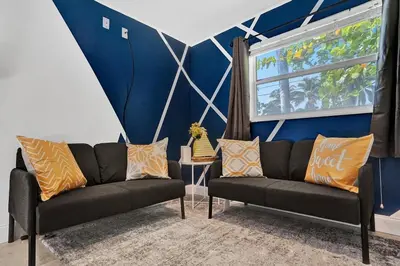 a living room with two black couches and a blue wall at Stylish 4 Bed 2 Bath Pool & Spa in Hollywood