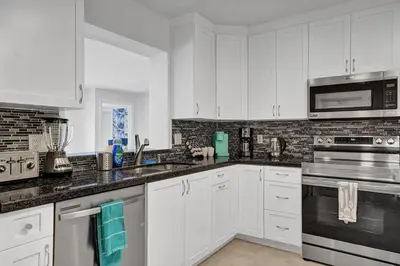 a kitchen with white cabinets and black appliances at Stylish 4 Bed 2 Bath Pool & Spa in Hollywood