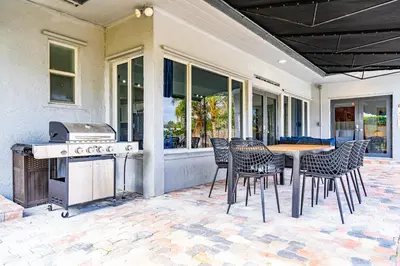 a patio with a table and chairs and a grill at Waterfront Pool Home Games, 10 min to Beach in Fort Lauderdale