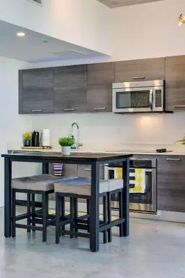 a kitchen with a table with stools and a microwave at Vibrant Downtown Haven with Rooftop Pool & Parking in Miami