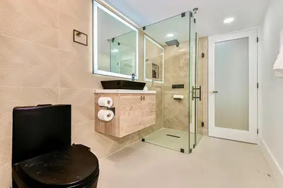 a bathroom with a sink and a glass shower at Boardwalk Steps from the Beach in Miami Beach