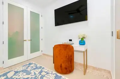 a room with a table and a television on a wall at Boardwalk Steps from the Beach in Miami Beach