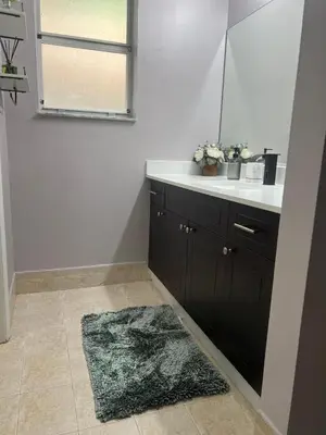 a bathroom with a sink and a mirror and a rug at Vacation QJR in Cutler Bay