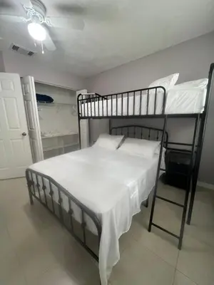 a bedroom with two bunk beds with white sheets at Vacation QJR in Cutler Bay