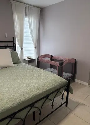a bedroom with a bed and a chair and a window at Vacation QJR in Cutler Bay