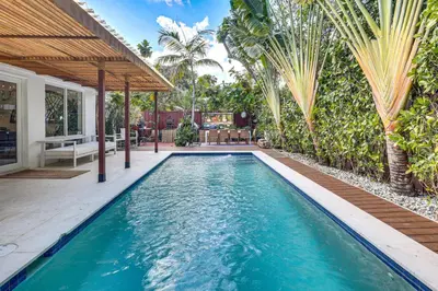 a swimming pool in the backyard of a house with palm trees at Tropical backyard with pool 10 min from Miami Beach! in Miami