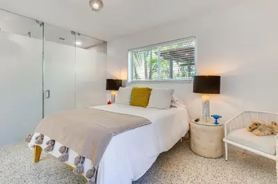 a bedroom with a bed and a window and a chair at Tropical backyard with pool 10 min from Miami Beach! in Miami