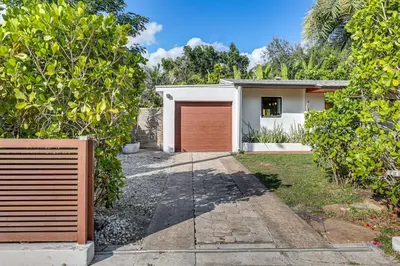 a garage with a red door in front of a house at Tropical backyard with pool 10 min from Miami Beach! in Miami