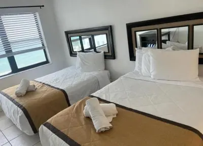 two beds in a room with two windows at Casablanca Beachfront with full kitchen in Miami Beach