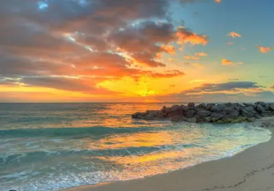 a sunset over the ocean with rocks on the beach at NEW House, Near Beaches, and MIA, Sleeps 8! in Westview