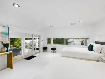 a white living room with a bed and a tv at Villa Zenora in Miami