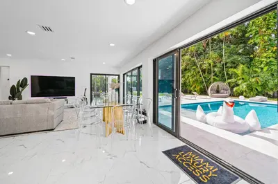 a living room with a swimming pool and a tv at Two Neighboring Villas in The Heart of Miami in Miami