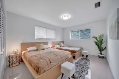 a bedroom with two beds and two windows at Two Neighboring Villas in The Heart of Miami in Miami