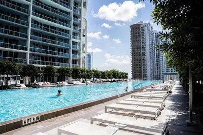 a large swimming pool with lounge chairs in a city at Brickell 35th Floor Residence with Saltwater Pool 5-Star Amenities in Miami