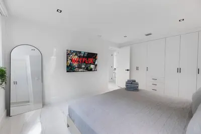 a white bedroom with a bed and a mirror at 2BR near Bal Harbour beautiful in Miami Beach