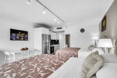 a white bedroom with a bed and a kitchen at Beachfront Resort Studio with 2 Queen beds, Balcony & Pool in Sunny Isles Beach