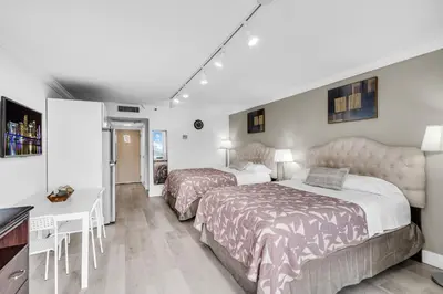 a hotel room with two beds and a desk at Beachfront Resort Studio with 2 Queen beds, Balcony & Pool in Sunny Isles Beach