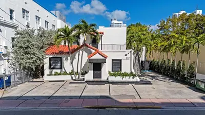 a white house with palm trees in front of a building at Retro Miami RareFREE Parking 1 Min to Beach in Miami Beach