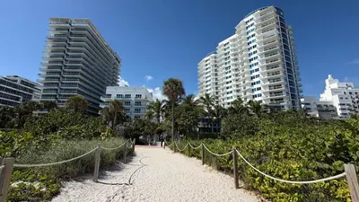 a beach with a fence and some tall buildings at Retro Miami RareFREE Parking 1 Min to Beach in Miami Beach