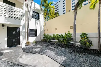 a patio with tables and palm trees in front of a building at Art Deco Gem by the Beach King Bed & Parking in Miami Beach