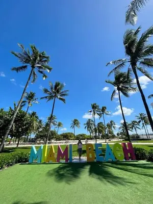 a person standing in front of a sign with palm trees at Art Deco Gem Steps to Beach in Miami Beach