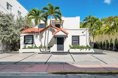 a white house with palm trees in front of it at Steps from Ocean Art Deco 1BR & Free Parking in Miami Beach