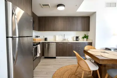 a kitchen with a table and a stainless steel refrigerator at Downtown Miami 2BR Retreat - Walk to Bayside & Port - Sleeps 6 in Miami
