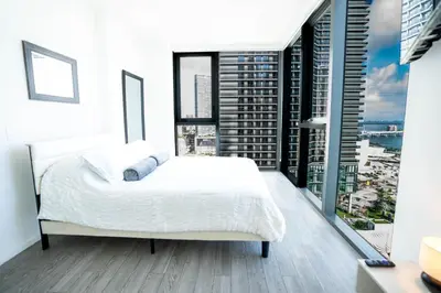 a bedroom with a white bed and large windows at Downtown Miami 2BR Retreat - Walk to Bayside & Port - Sleeps 6 in Miami