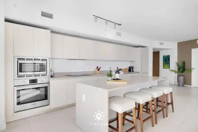 a kitchen with white cabinets and a counter with stools at Oceanline 3BR Corner Balcony & Calm Seas in Hollywood