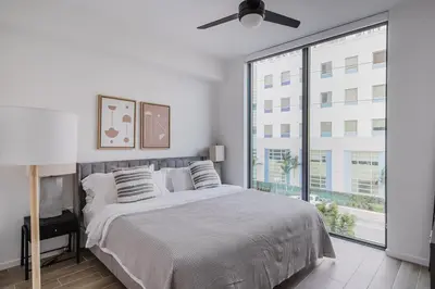 a white bedroom with a bed and a large window at Blueground Coral Gables pool wd nr Vizcaya MIA-125 in Miami