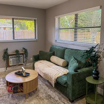 a living room with a green couch and a table at 20 Off The Jungle House 10 min Beach & FLL Airport in Fort Lauderdale