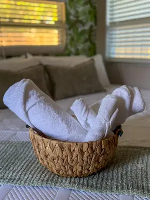 a basket of towels sitting on a bed at 20 Off The Jungle House 10 min Beach & FLL Airport in Fort Lauderdale