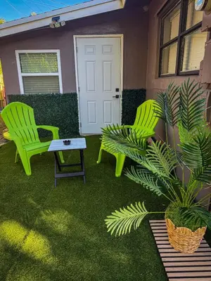 two green chairs and a table in front of a house at 20 Off The Jungle House 10 min Beach & FLL Airport in Fort Lauderdale