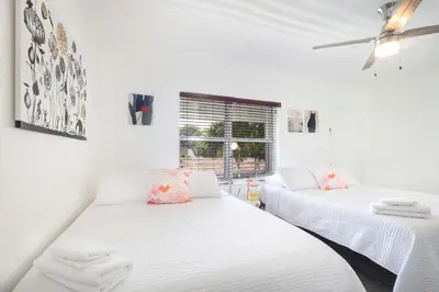 two beds in a room with white walls and a window at B08 10 MIN FROM MIAMI BEACH, Studio, Miami Design District & Wynwood in Miami