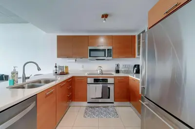 a kitchen with wooden cabinets and a stainless steel refrigerator at Midtown Miami Marvel- Heated Pool & Prime Location in Miami
