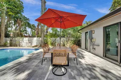 a table with a red umbrella next to a pool at Cute 3 Bedroom 2 Bathroom Pool Home in Hollywood