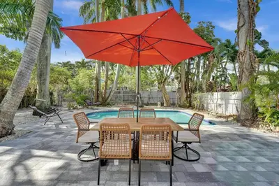a table with a red umbrella next to a pool at Cute 3 Bedroom 2 Bathroom Pool Home in Hollywood