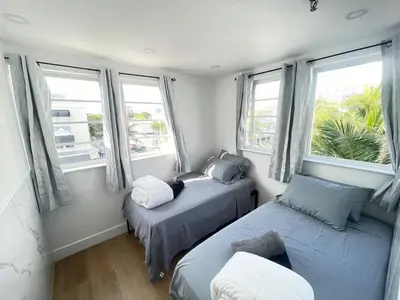 a bedroom with two beds and two windows at The Azure Terrace Loft in Miami Beach