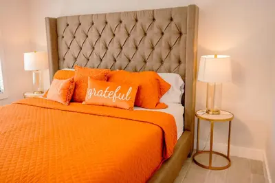 an orange bed with orange pillows and two lamps at Bimini Bliss Waterfront Pool Retreat in Fort Lauderdale